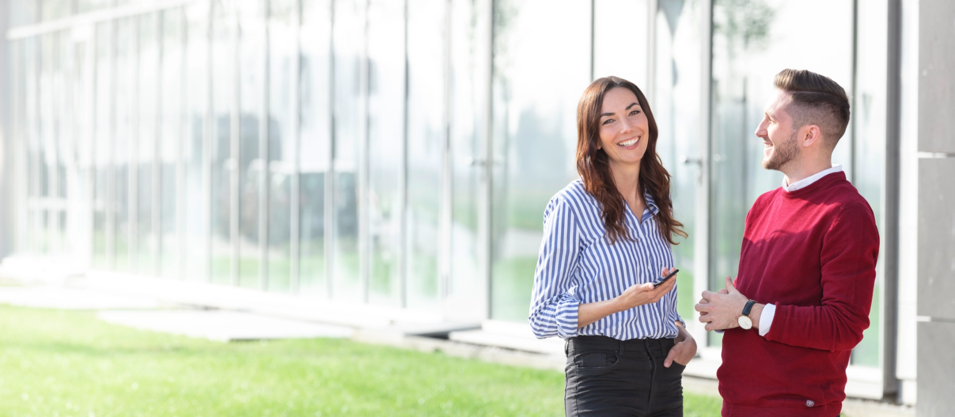 Eine Mitarbeiterin steht mit ihrem Kollegen vor der Firmenzentrale von msg in Ismaning