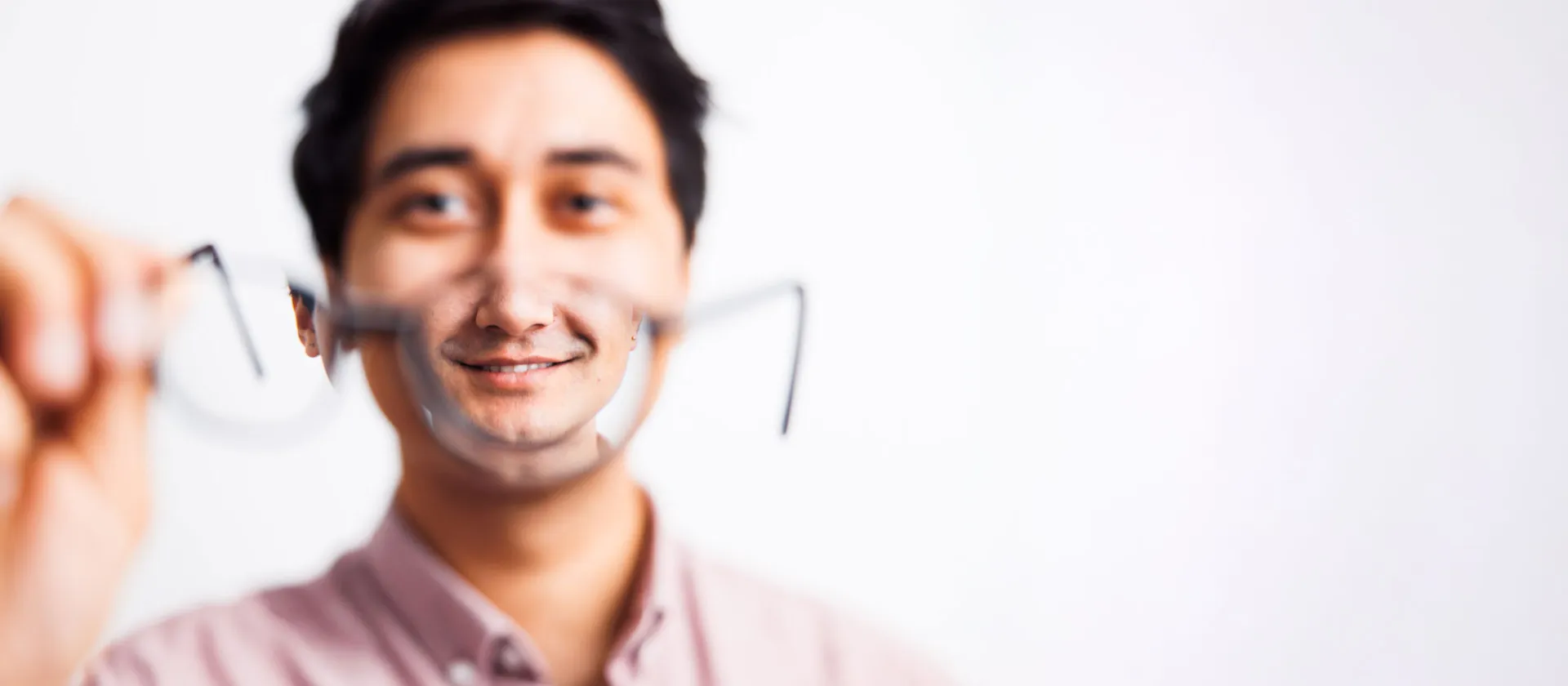 Close-up of a smiling professional holding glasses towards the camera, symbolizing clear vision, innovation, and strategic perspective, representing msg Plaut’s expertise in business transformation and digital solutions.