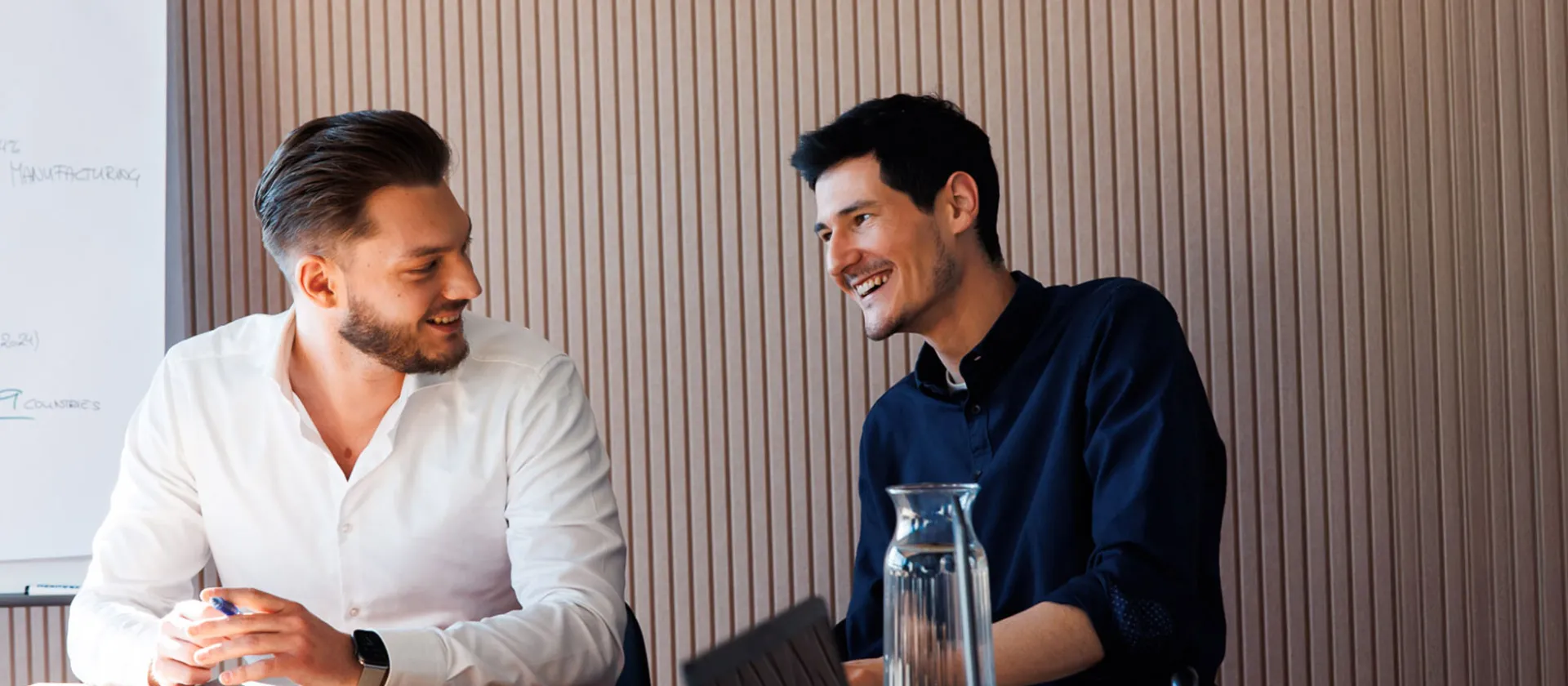 The picture shows two men sitting together, discussing a project.