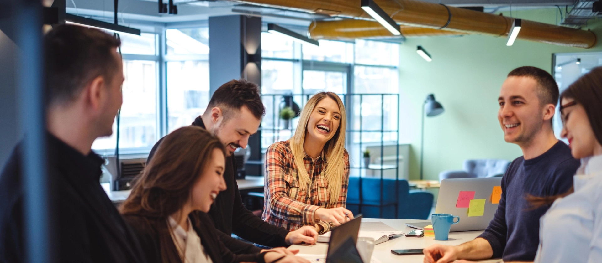 Büroszene lachender Kolleginnen und Kollegen in einem Projektbüro im Bereich Telecommunications