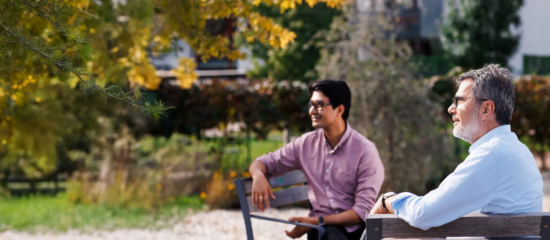 Two professionals sitting on a park bench, engaged in an informal outdoor conversation, reflecting the company’s commitment to collaboration, innovation, and people-centric solutions.