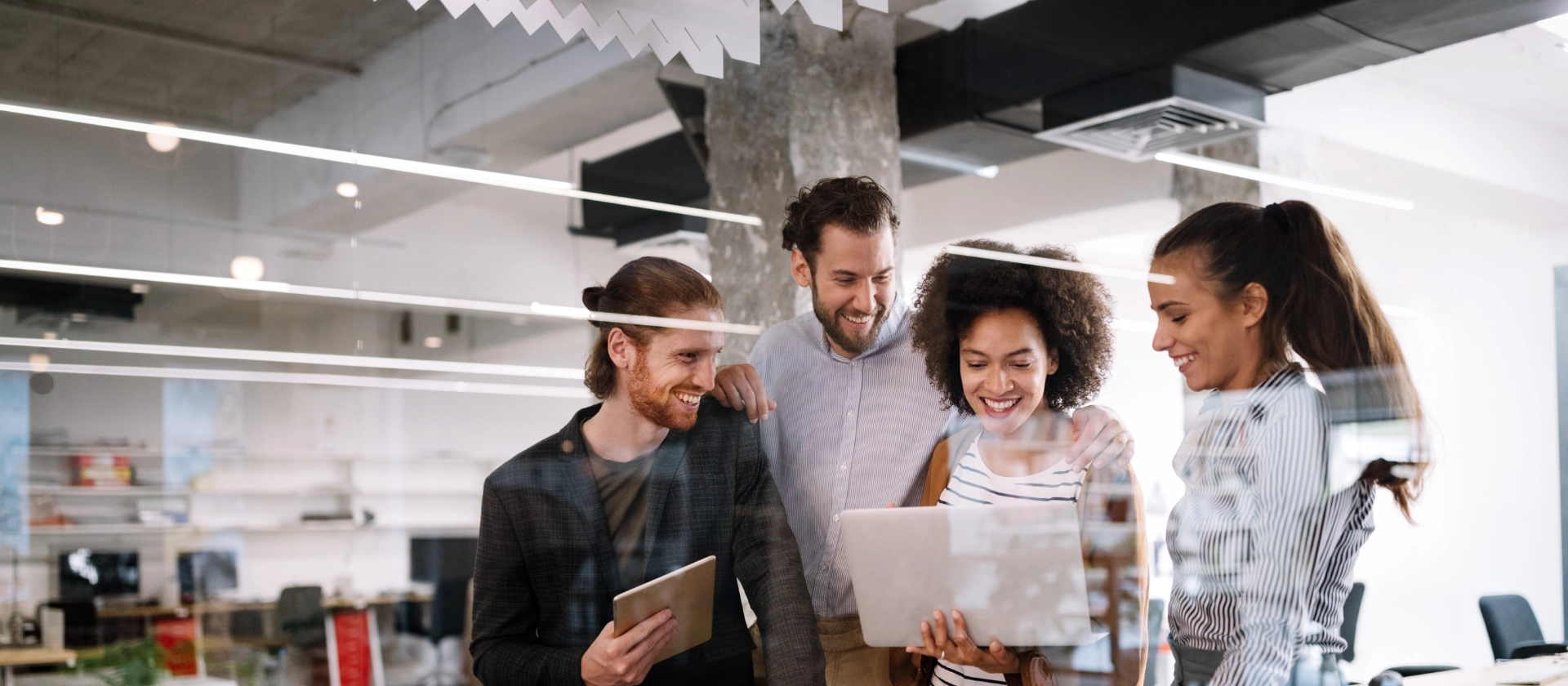 Eine gemischte Gruppe Mitarbeitender aus dem Bereich Test & Quality Management betrachten Arbeitsergebnisse auf einem Laptop