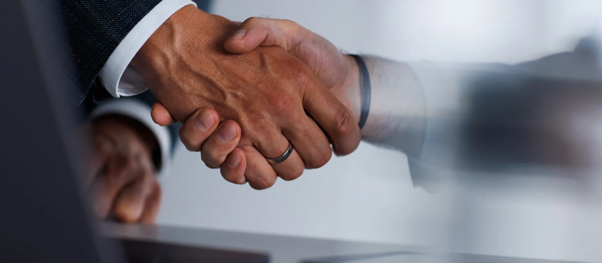 Close-up of two business professionals shaking hands across a table, symbolizing successful partnership or agreement in a corporate setting.