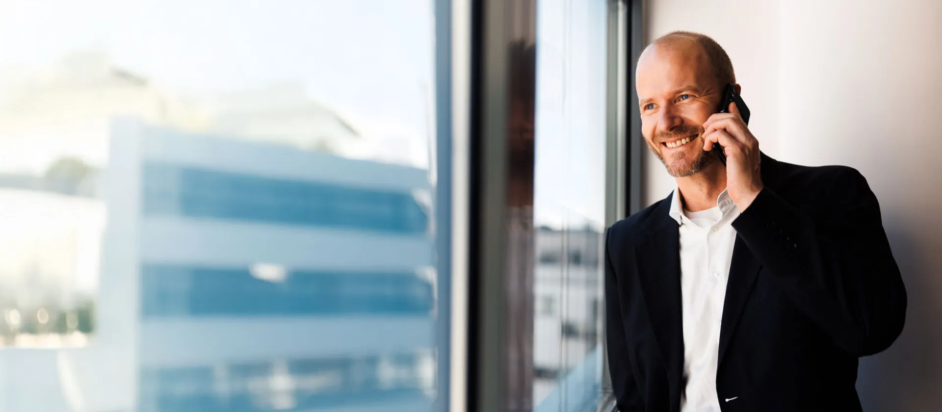 Business professional in a modern office, smiling while making a phone call, symbolizing confident communication and digital business consulting.