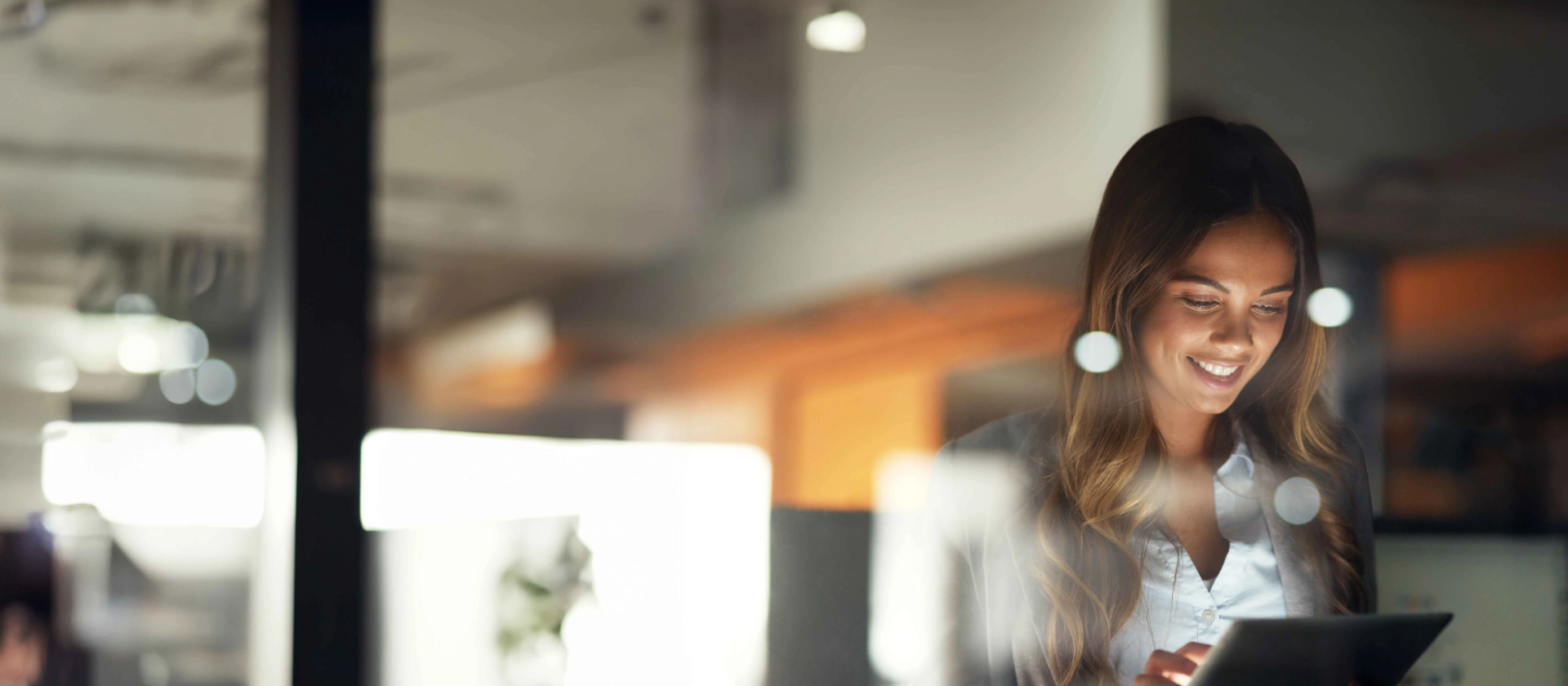 Frau schaut lächelnd auf ein Tablet, was sie in den Händen hält