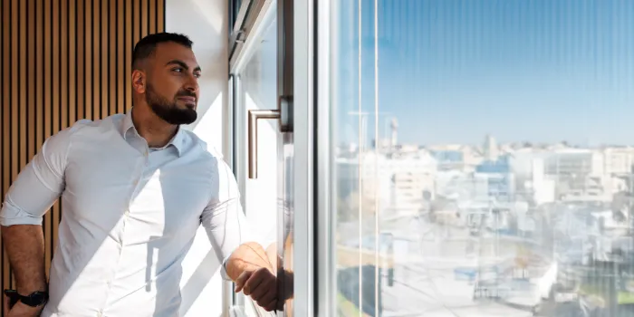 Confident business professional looking out of a modern office window with a cityscape view, symbolizing strategic thinking, leadership, and digital transformation.