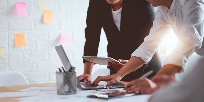 Business team collaborating on a digital project using laptops and tablets at a modern office workspace.