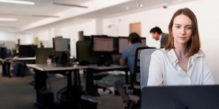 oung professional woman working on a laptop in a modern open-plan office 
