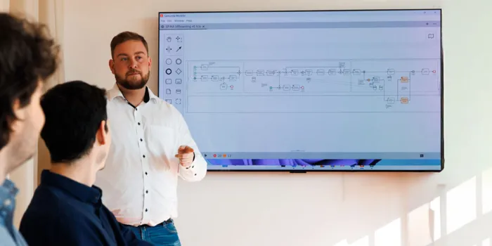 Business consultant presenting a digital process model to colleagues, showcasing msg Plaut’s expertise in process optimization and digital transformation solutions.
