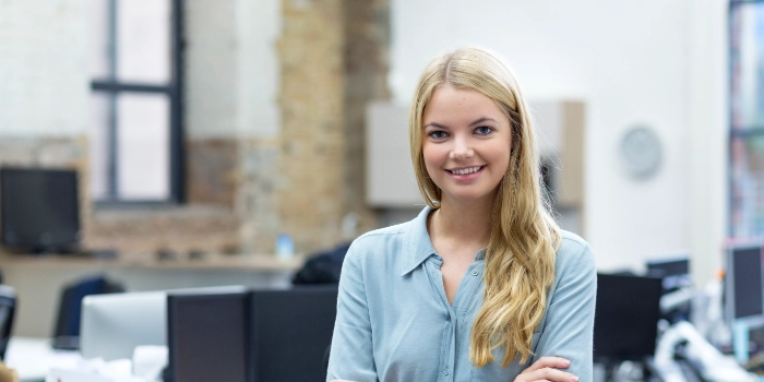 Eine Auszubildende steht in einem Office zwischen Schreibtischen
