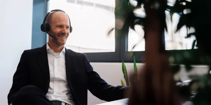 Smiling business professional in a video call wearing a headset in a bright modern office