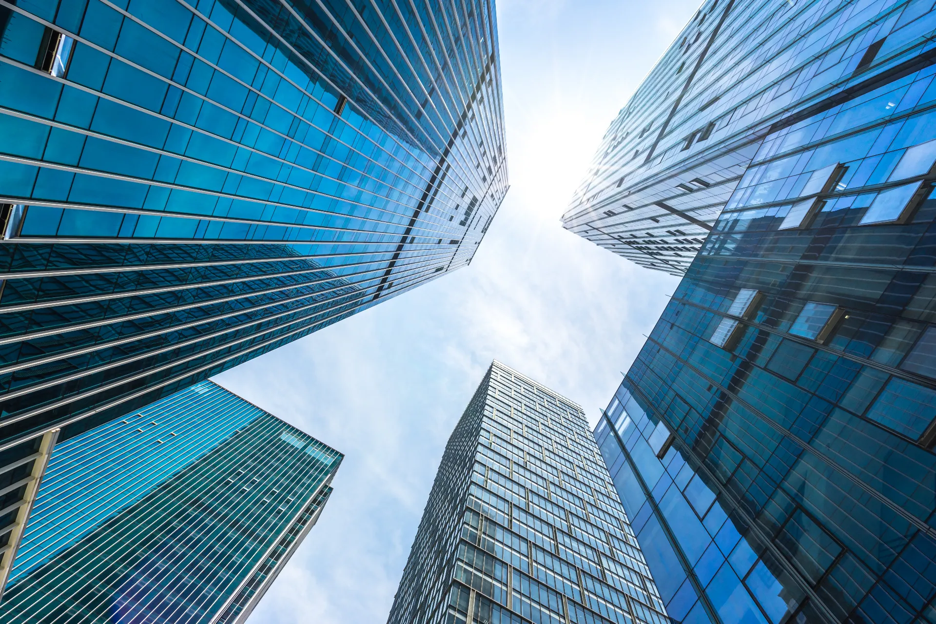 View looking up at modern glass skyscrapers against a bright sky, symbolizing innovation, growth, and corporate vision.