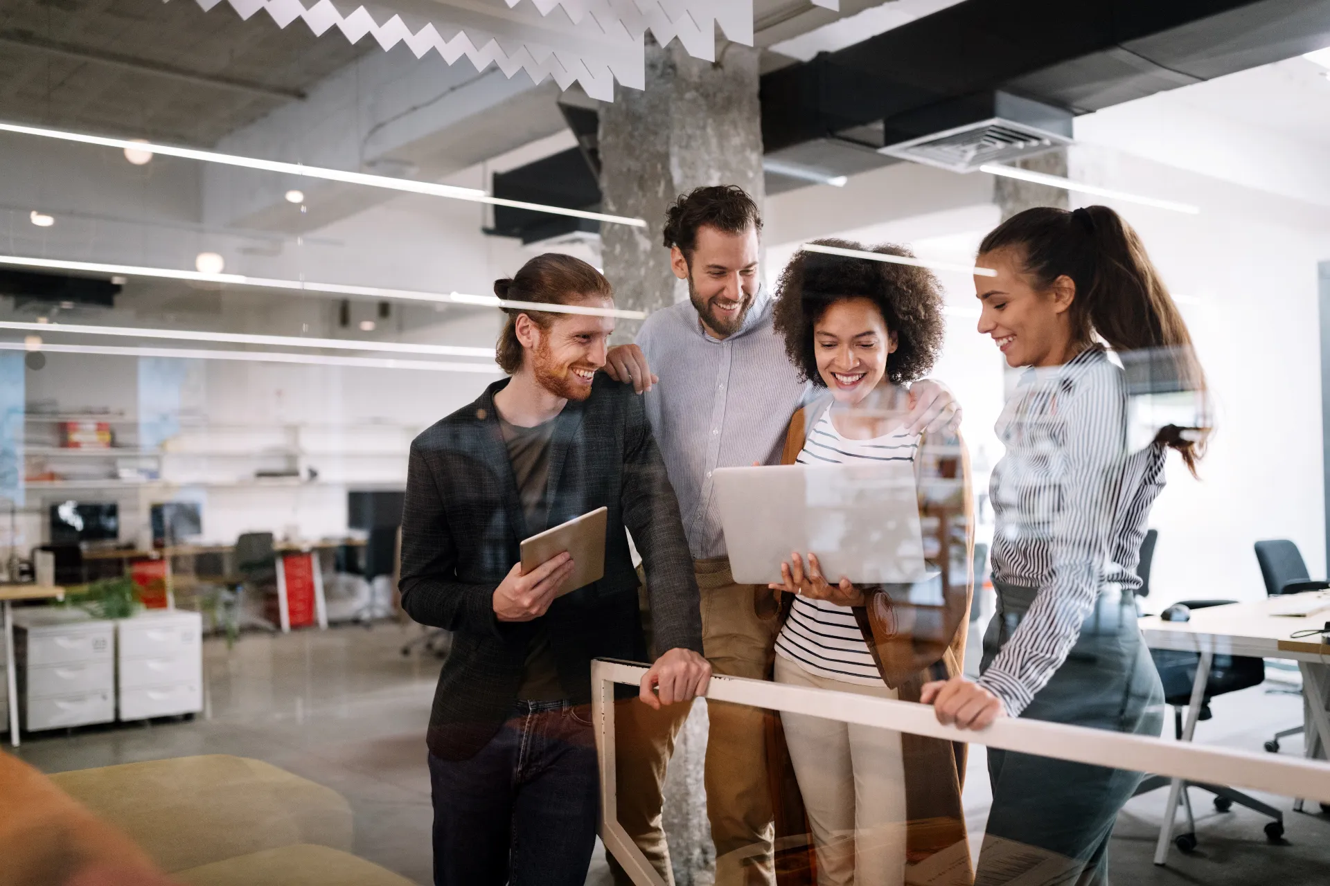 Eine gemischte Gruppe Mitarbeitender aus dem Bereich Test & Quality Management betrachten Arbeitsergebnisse auf einem Laptop