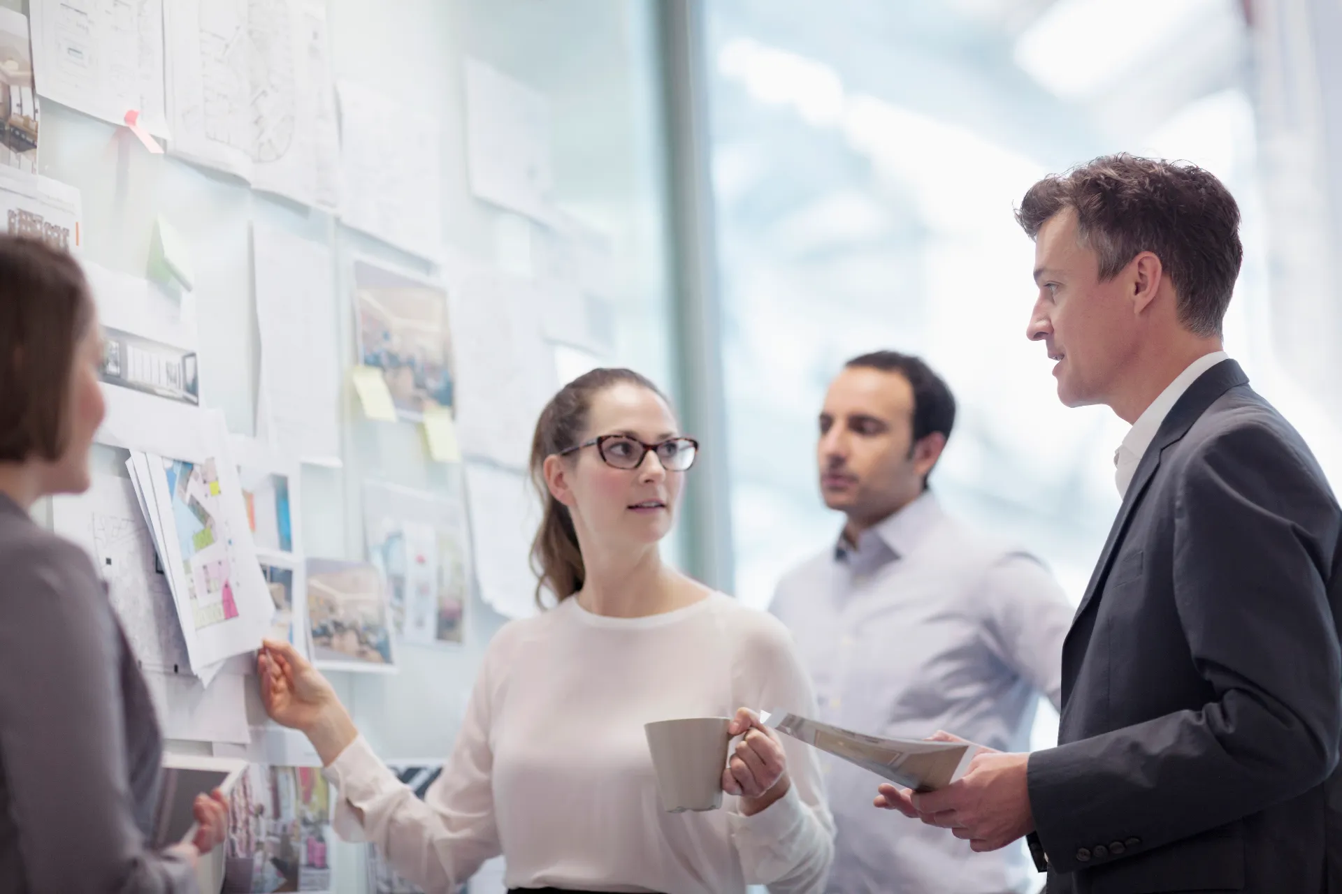 Zwei Frauen und zwei Männer aus der Geschäftseinheit Insurance besprechen sich vor einem Whiteboard mit Notizen