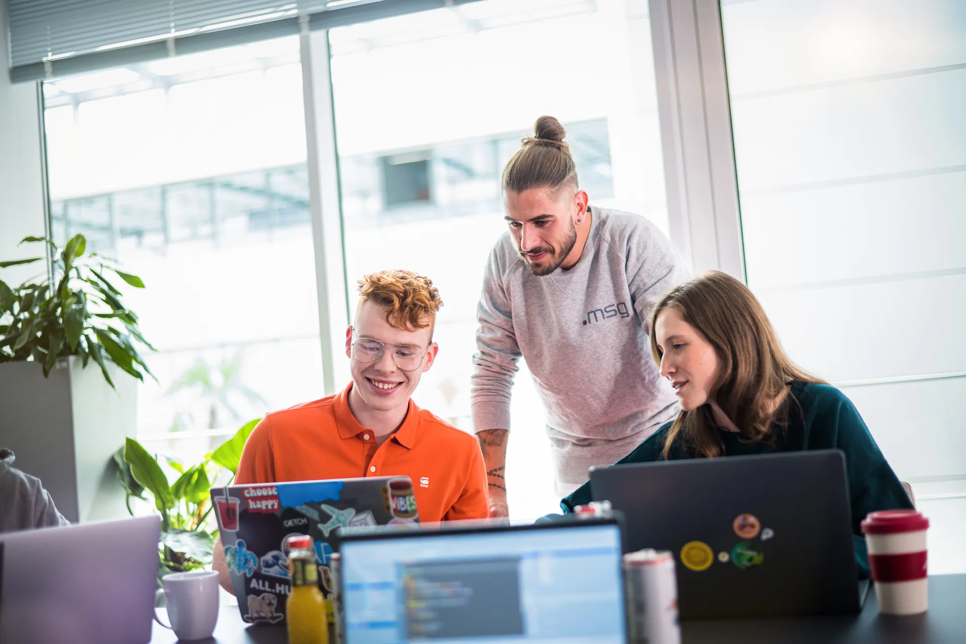 Workshop-Trainer schaut zwei Teilnehmenden helfend über die Schulter