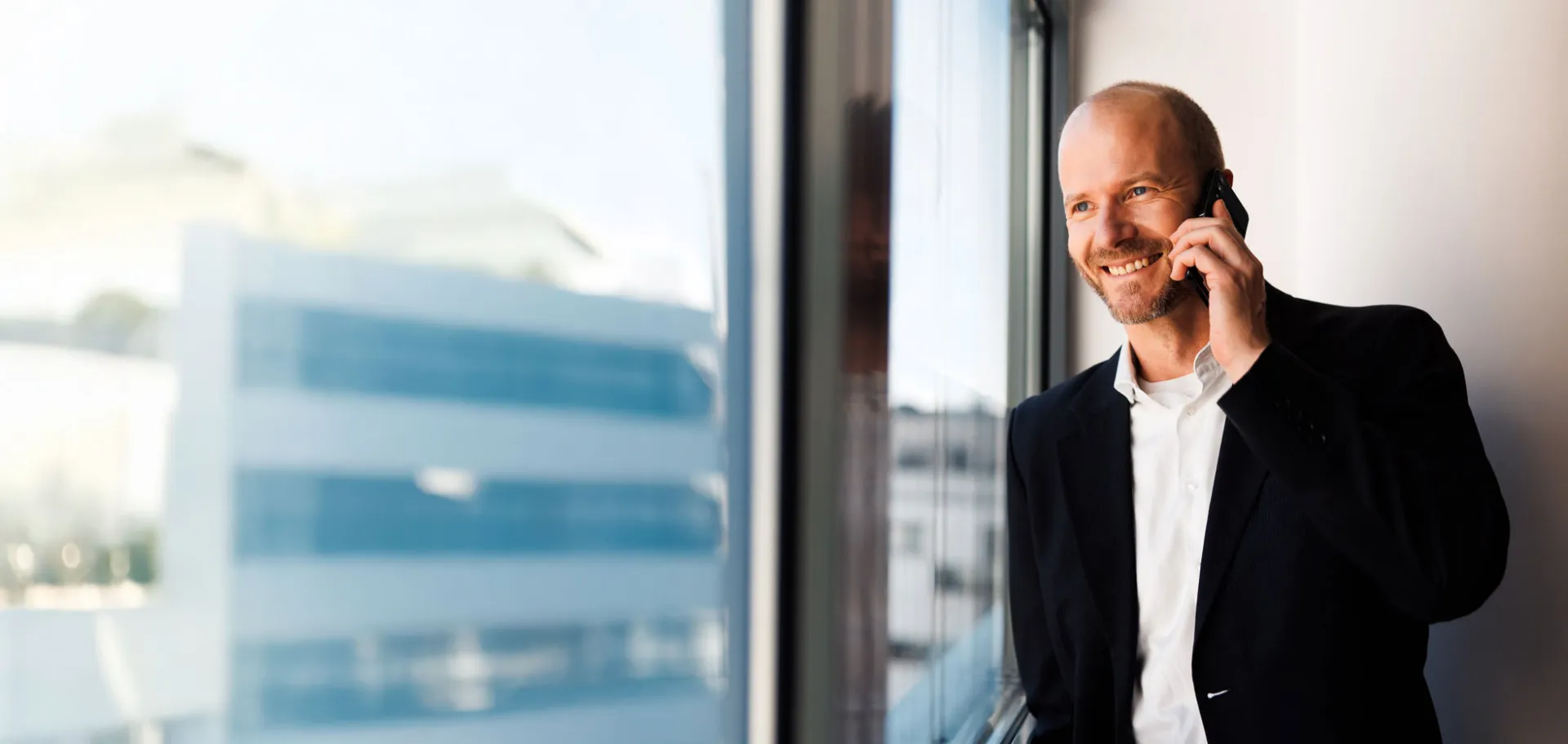 Business professional in a modern office, smiling while making a phone call, symbolizing confident communication and digital business consulting.