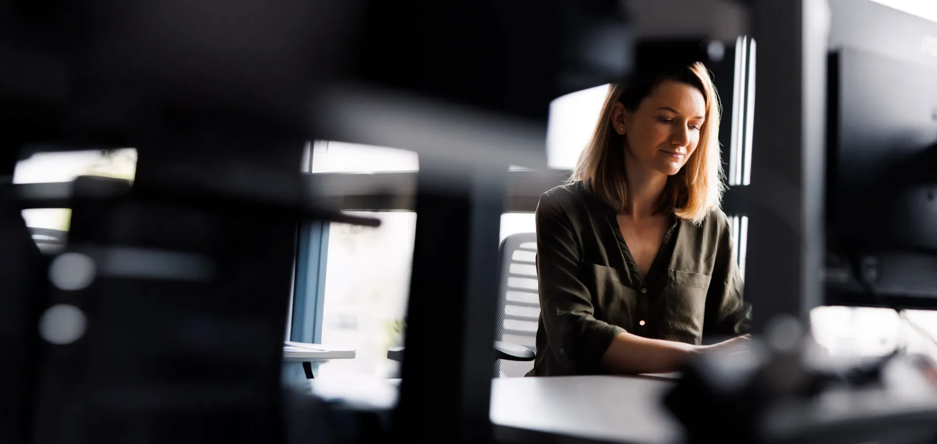 Woman working at desk in modern office, focusing on a project in digital transformation and technology consulting.