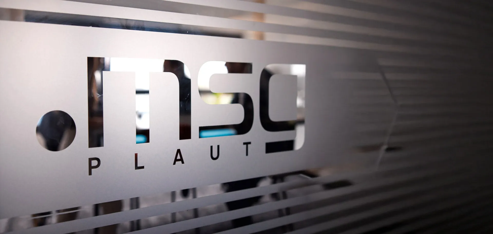 Close-up of the msg Plaut logo on a glass office partition.