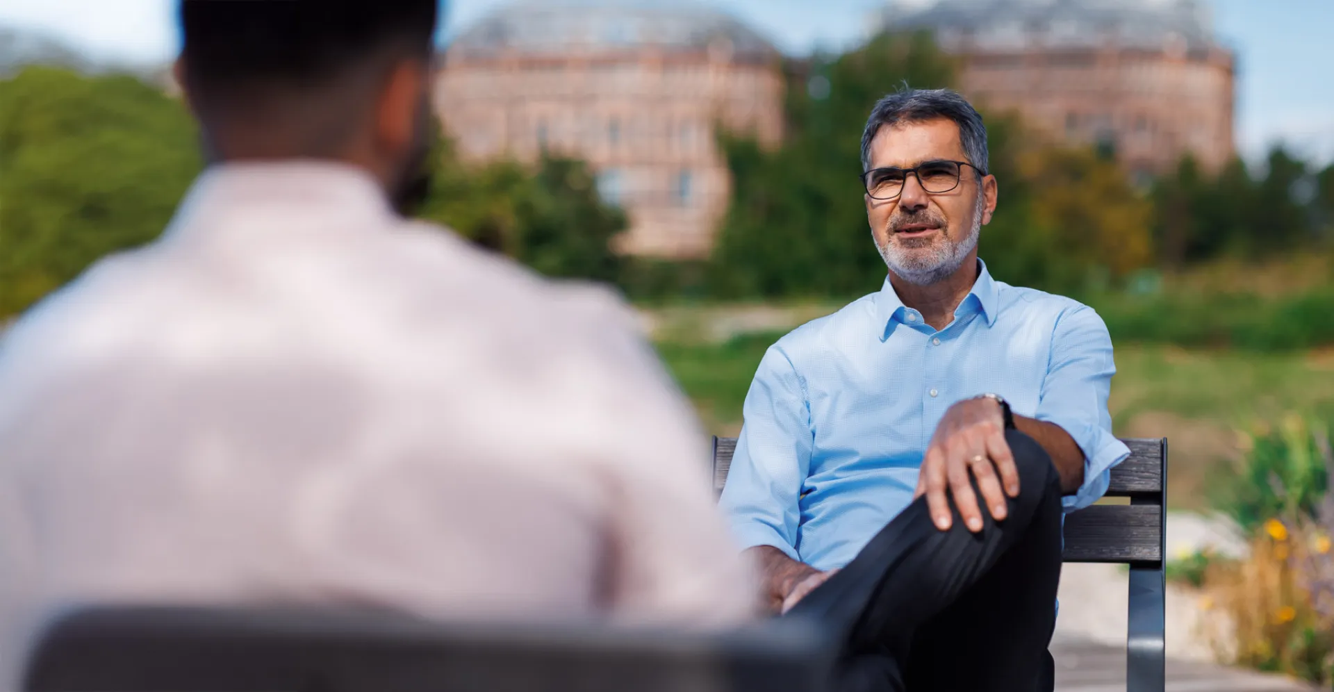 Senior executive discussing ESG strategies and corporate responsibility in an outdoor setting, with the historic Gasometer Vienna in the background.