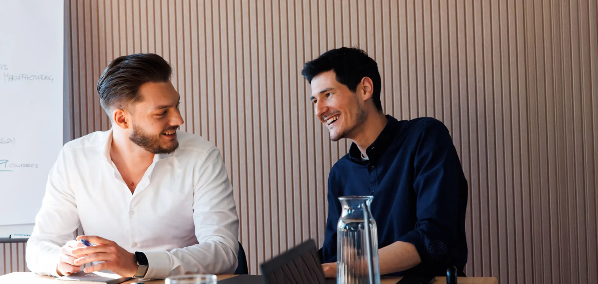 The picture shows two men sitting together, discussing a project.